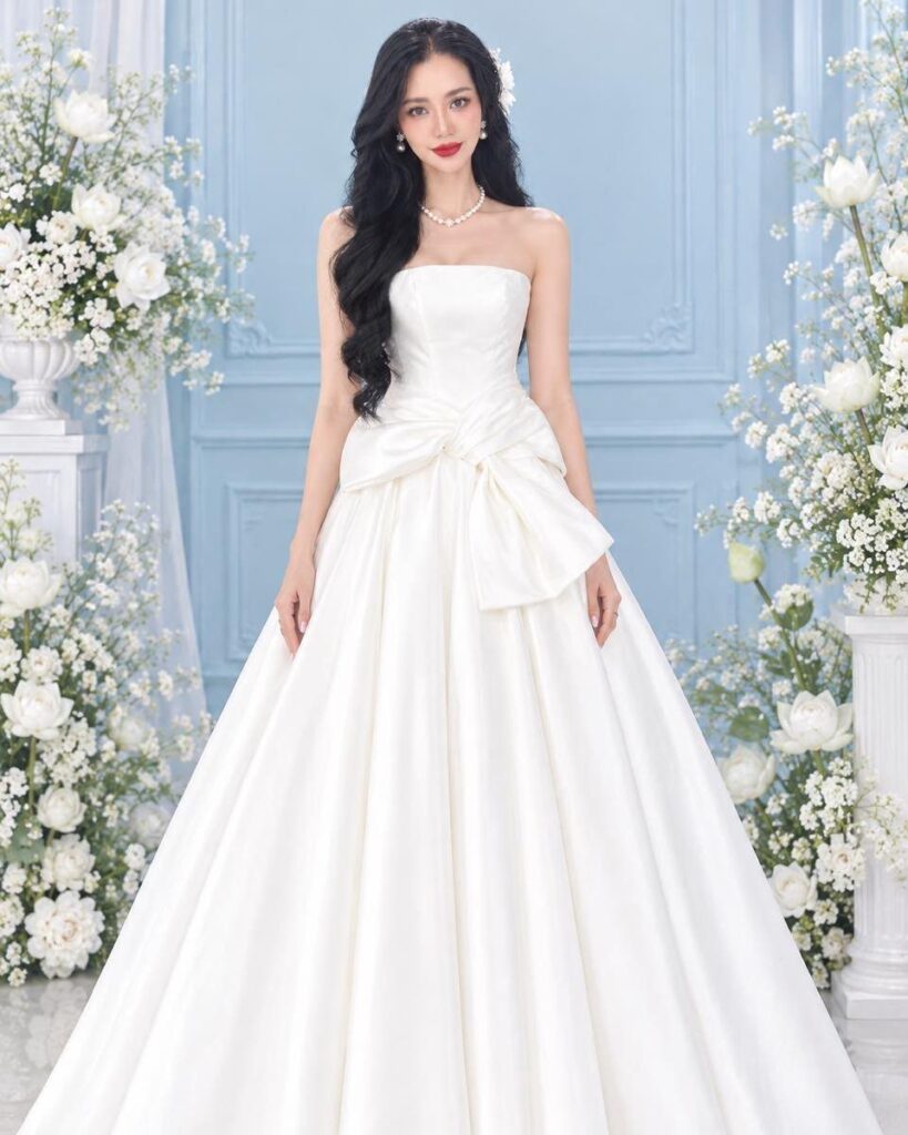 Woman in a white strapless wedding dress with a large bow at the waist.